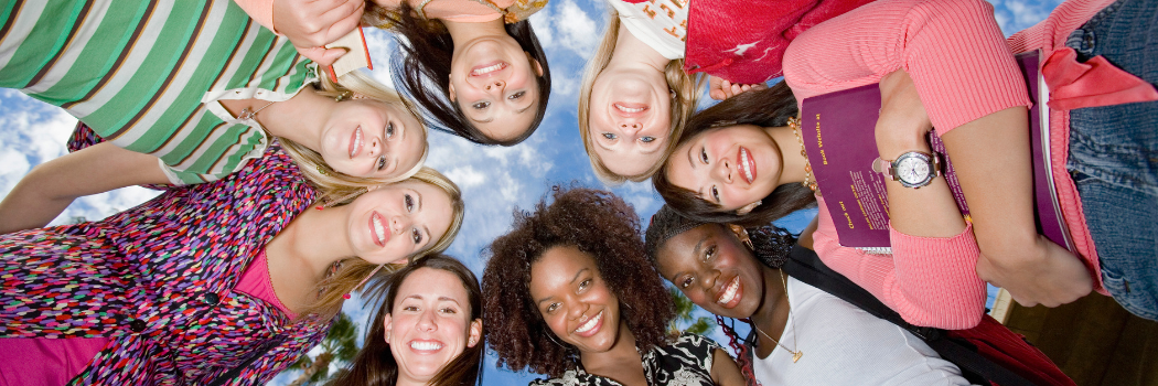 circle of young women smiling in a group photo (looking down at the camera)